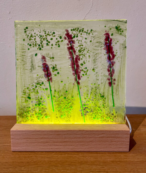 Een ambachtelijk handgemaakt glascreatie met als onderwerp lavendel tussen het gras.