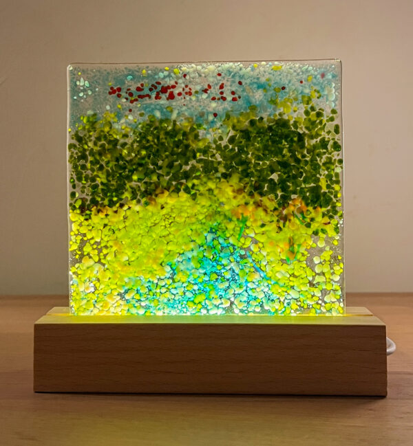 Handgemaakt glaswerk op verlichte sokkel: een impressie van een zomers bospad